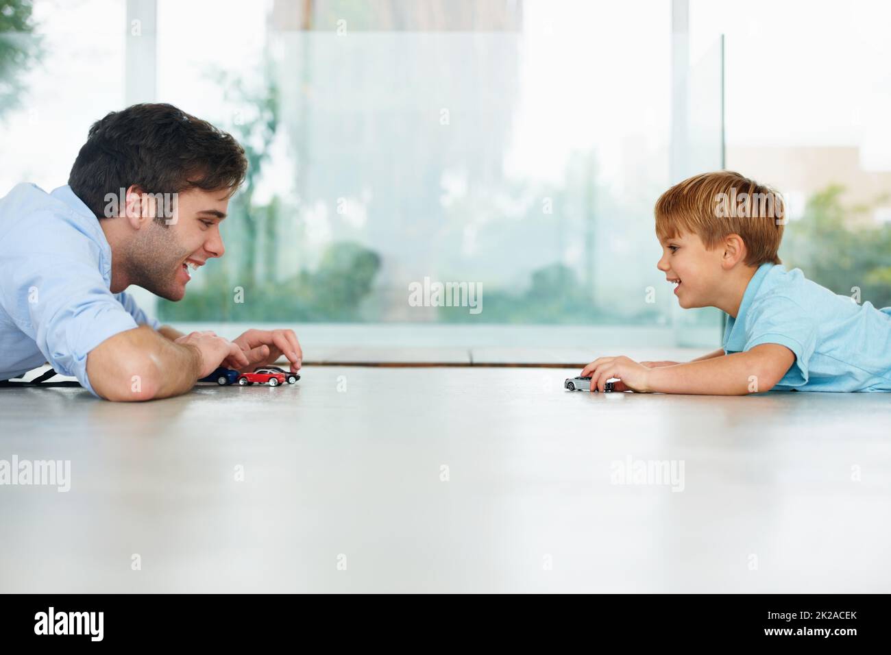 Godendo un po' di tempo padre-figlio. Un ragazzo carino e suo padre che giocano con le auto giocattolo sul pavimento. Foto Stock