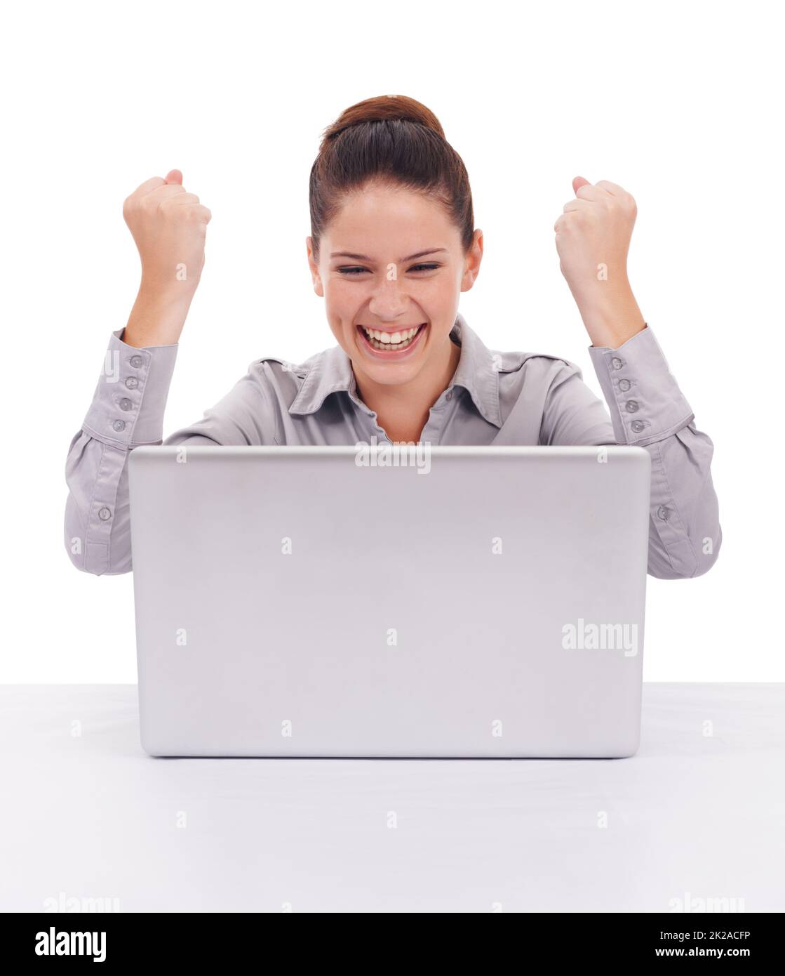 Trovare divertimento online. Scatto di una giovane donna estatica seduta davanti a un notebook isolato di bianco. Foto Stock