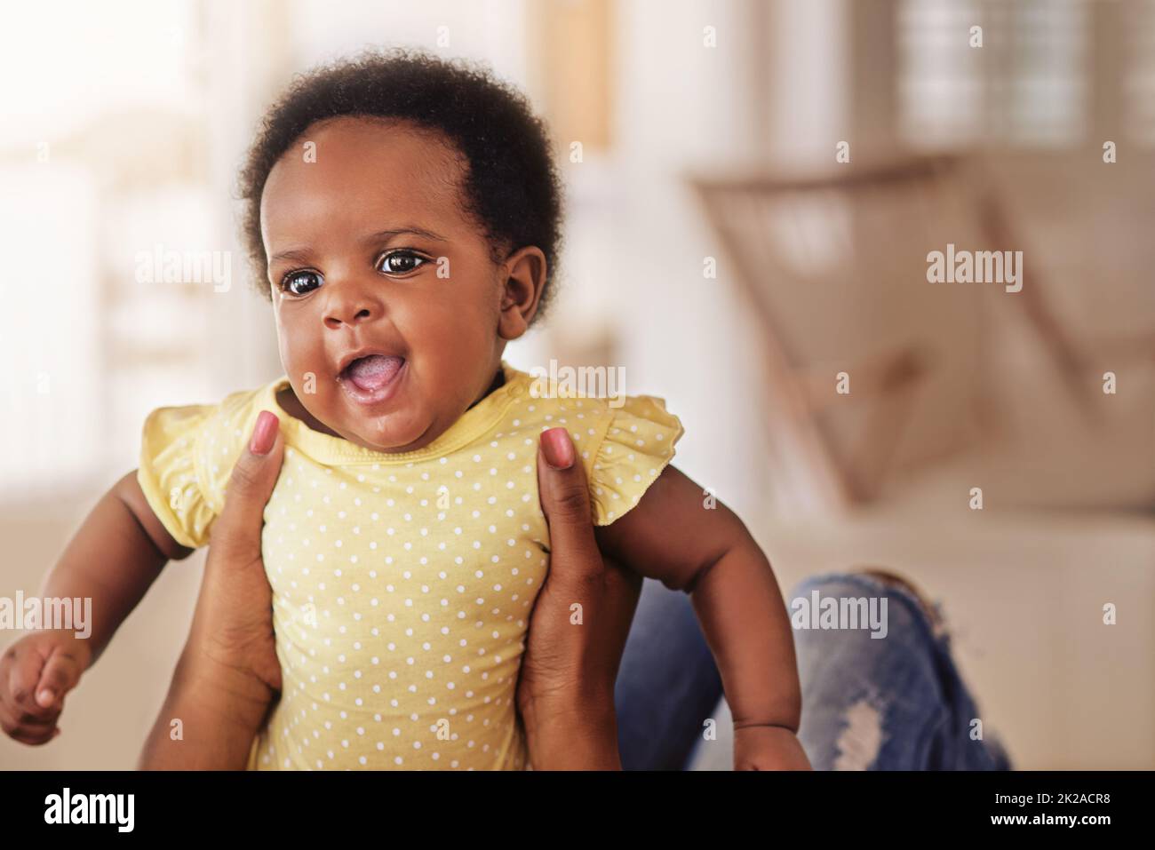 Palpita un piccolo miracolo prezioso. Shot di una bambina che guarda felice come sua madre la tiene in su. Foto Stock