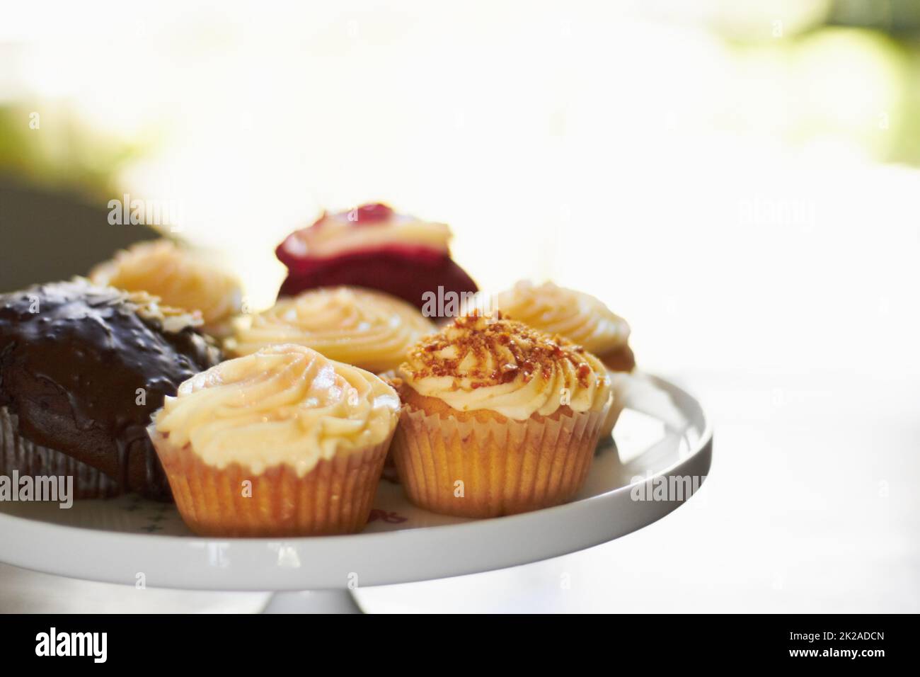 Svetta piccoli piaceri dolci. Un vassoio di un assortimento di deliziosi cupcake con glassa cremosa. Foto Stock