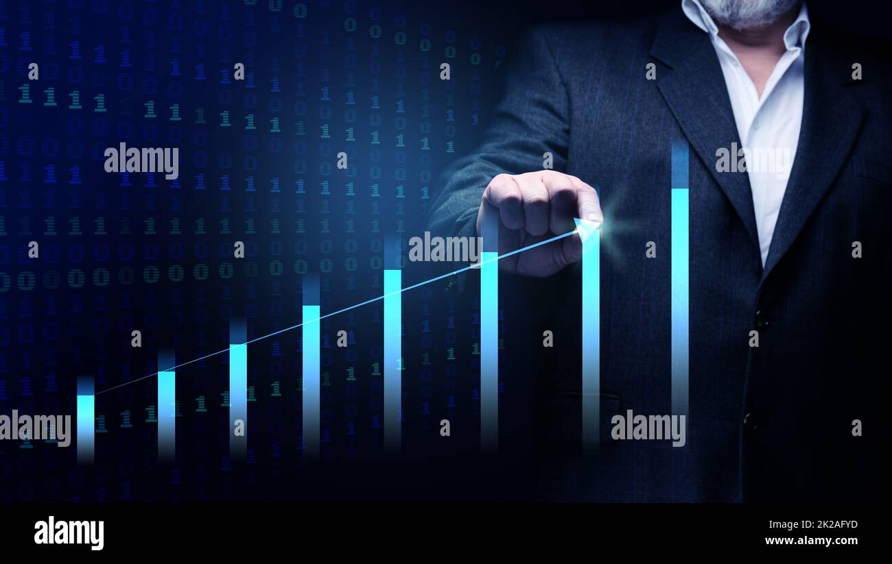 l'uomo d'affari in un vestito si leva davanti ad un grafico olografico con le figure crescenti, la crescita di affari, reddito alto. Negoziazione in borsa Foto Stock