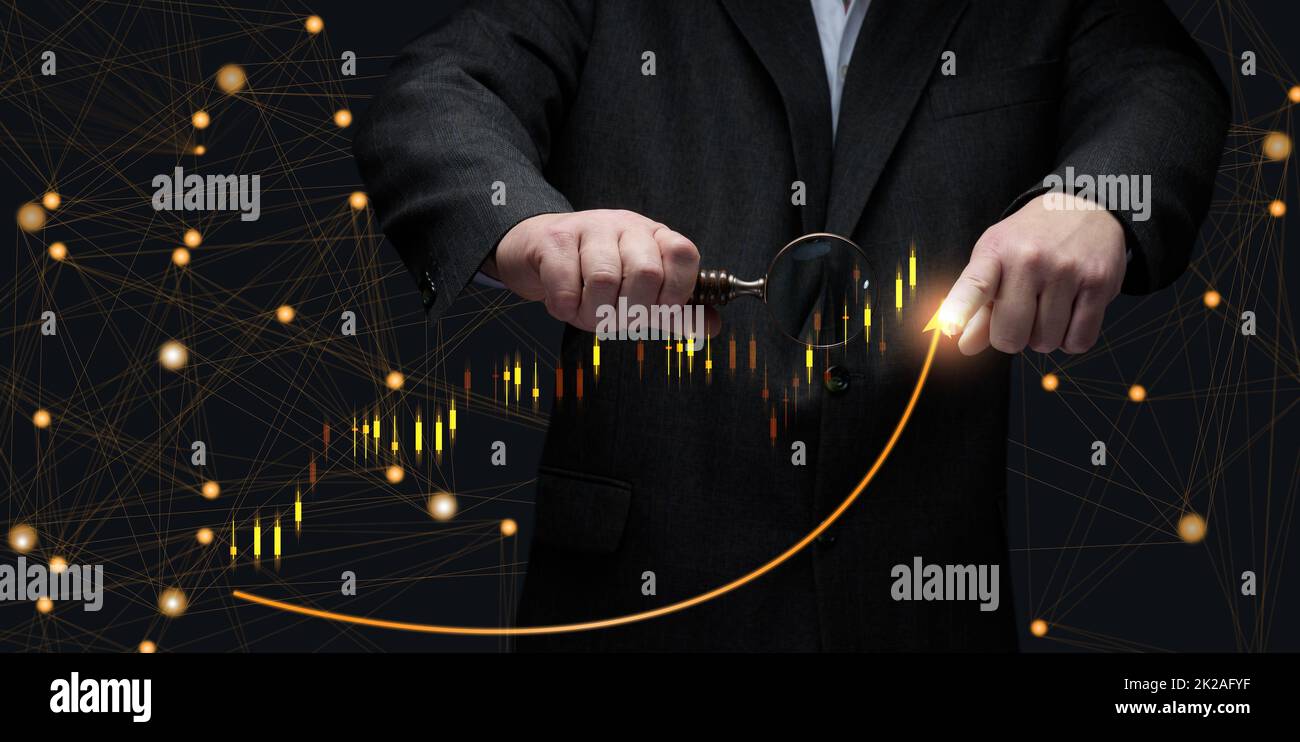 l'uomo d'affari in un vestito si leva davanti ad un grafico olografico con le figure crescenti, la crescita di affari, reddito alto. Negoziazione in borsa Foto Stock