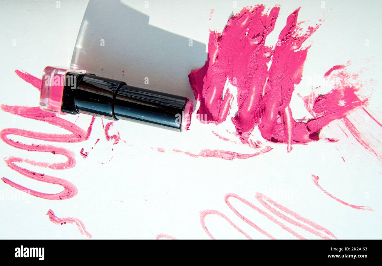 Un tubo di rossetto su macchie di rossetto rosso, isolato su sfondo bianco. Texture e ombra cremose per il trucco. Vista dall'alto Foto Stock