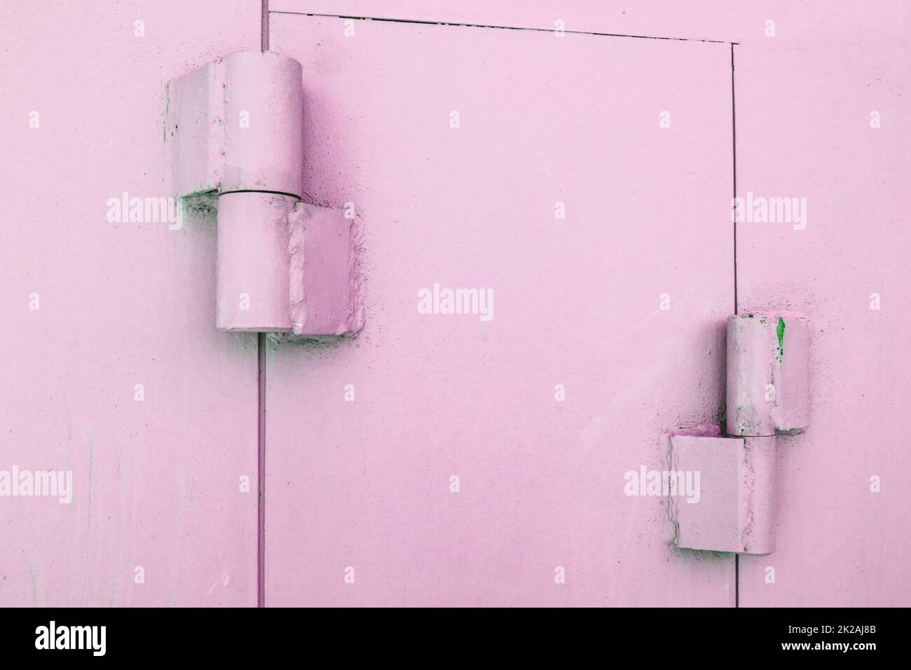 Primo piano delle cerniere metalliche sui cancelli di un garage in metallo, verniciato di rosa, all'aperto Foto Stock
