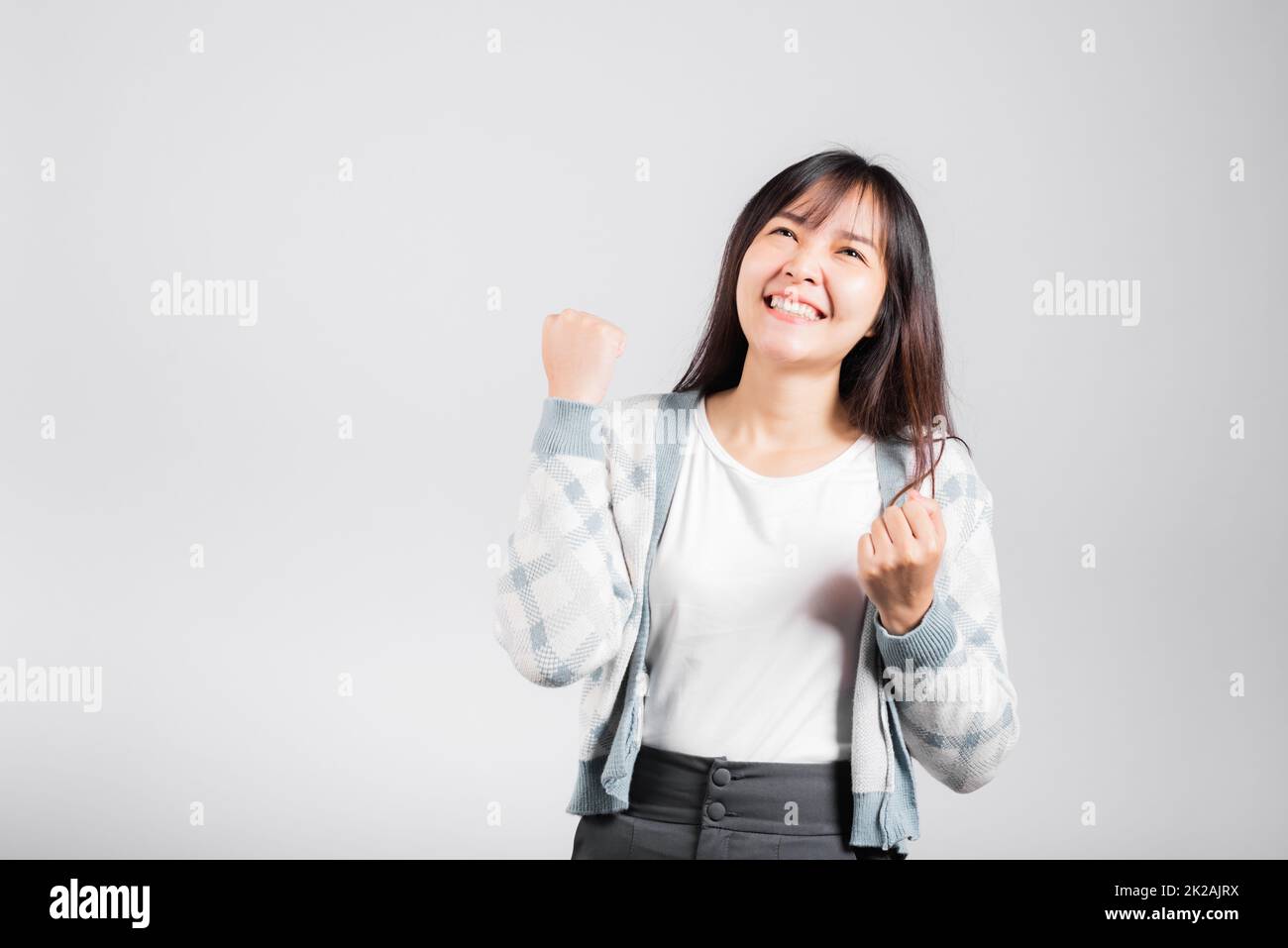 Sorridente donna felice fa pugni alzati in su celebrando il suo gesto di successo di vincita Foto Stock