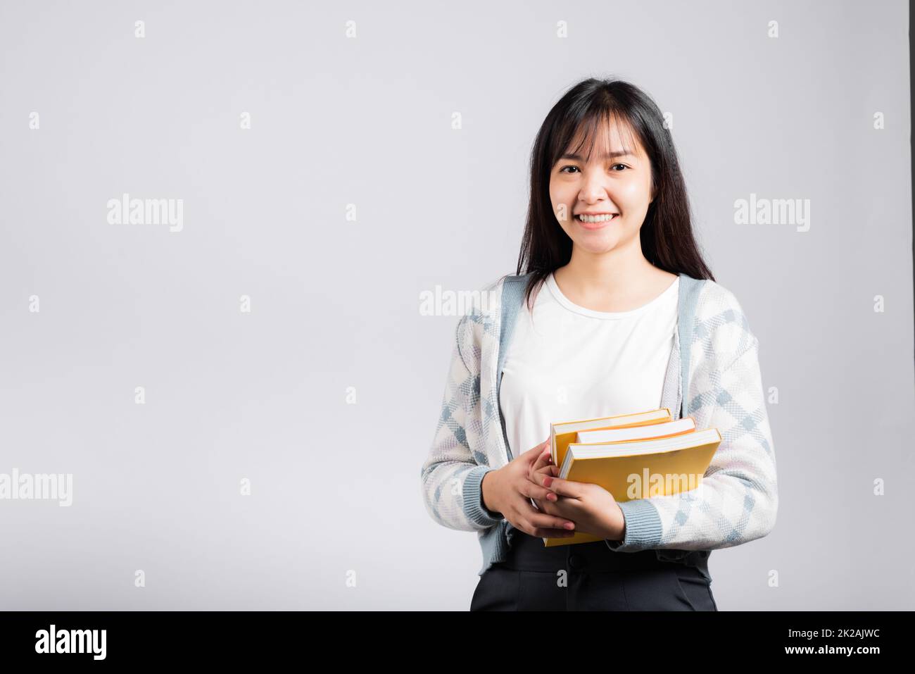 Donna giovane sorridente tenendo e abbracciare abbracciare il libro preferito per l'amante Foto Stock