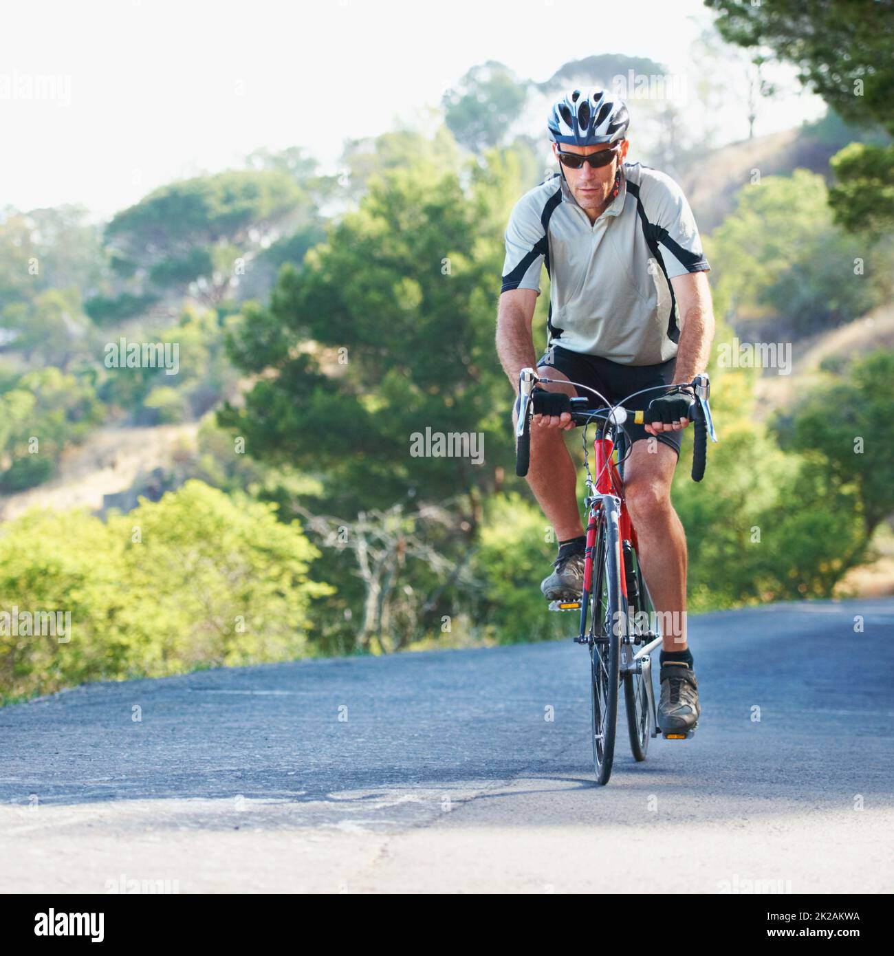 La determinazione lo porterà al vertice. Scatto di un pilota solista che pedalerà lungo una strada rurale. Foto Stock