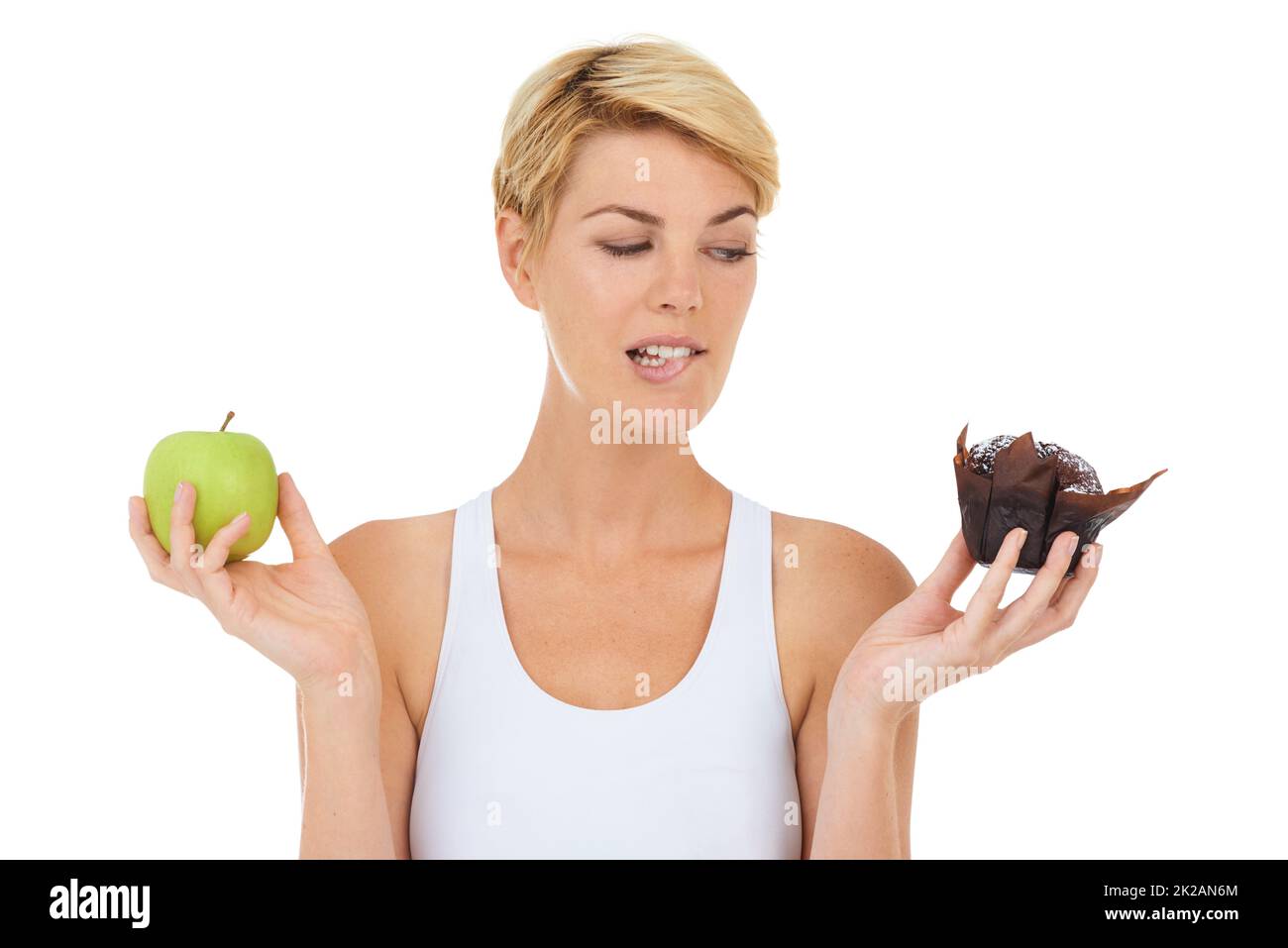 Ooooh non dovrei, ma è così allettante. Scatto ritagliato di una giovane donna che tiene una mela e dolce trattare aspetto indecisive-isolato immagine. Foto Stock