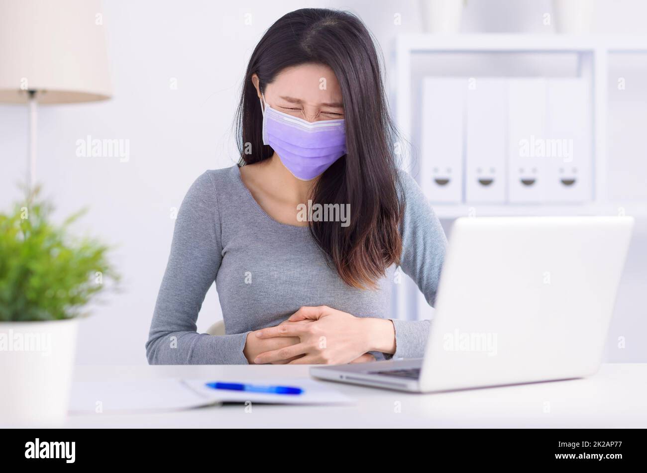 Giovane donna che soffre di dolori addominali in office Foto Stock