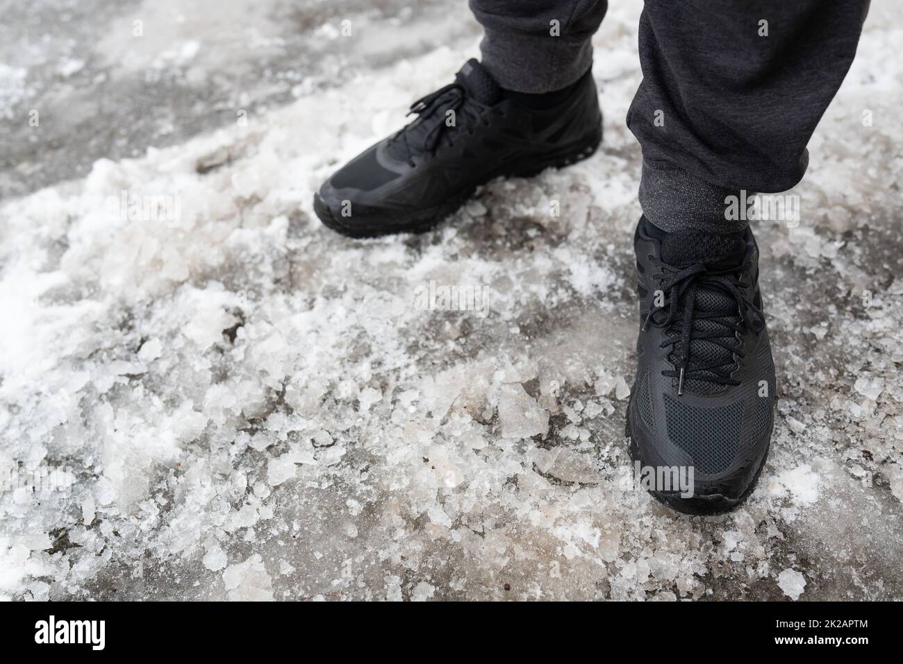 Le sneaker impermeabili uomo d'inverno si trovano su una strada ghiacciata, scarpe per passeggiate invernali. Passeggiate all'aria aperta. Foto Stock