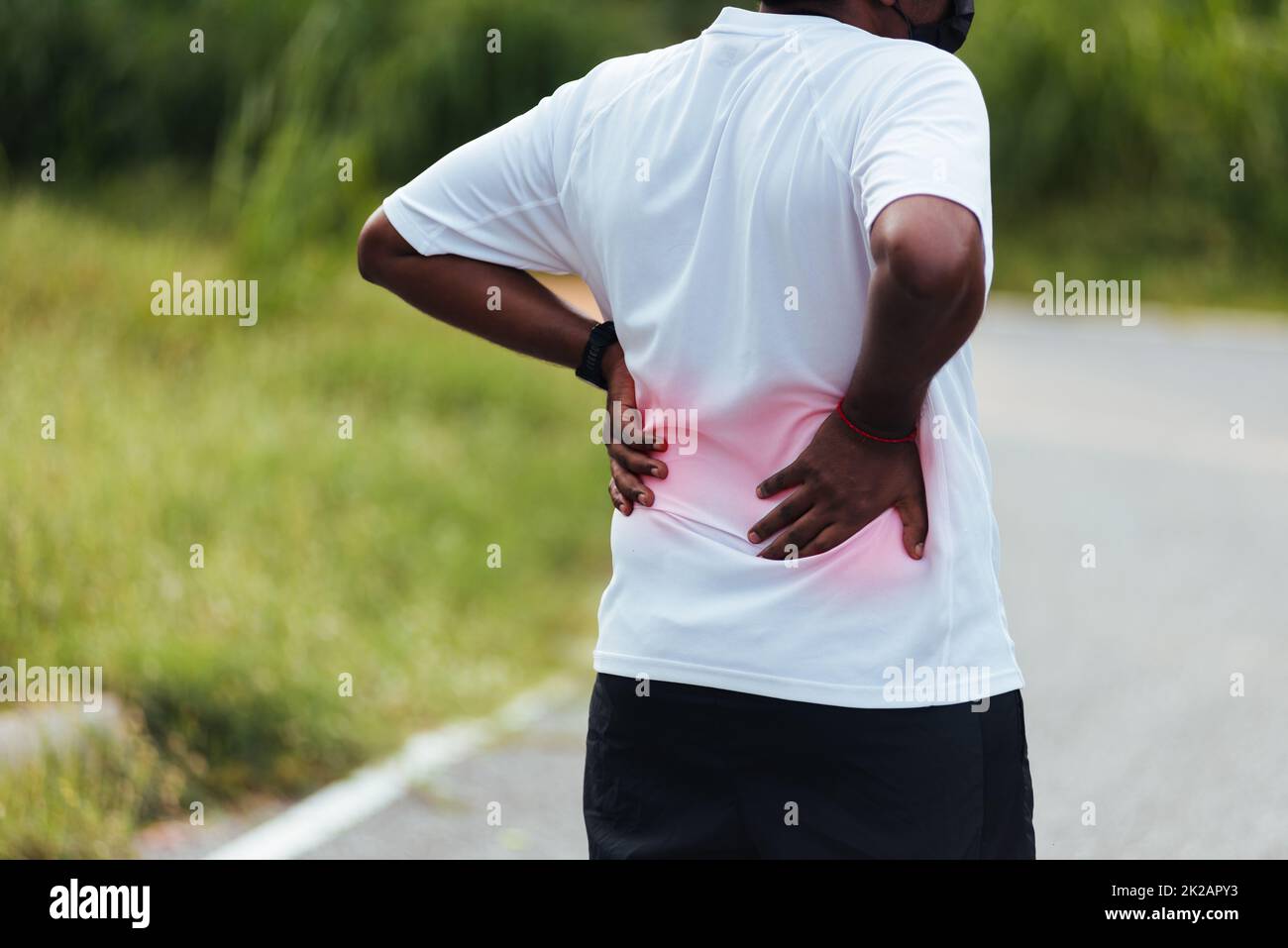 runner uomo nero indossare orologio sentire dolore sulla sua spina dorsale parte posteriore bassa Foto Stock