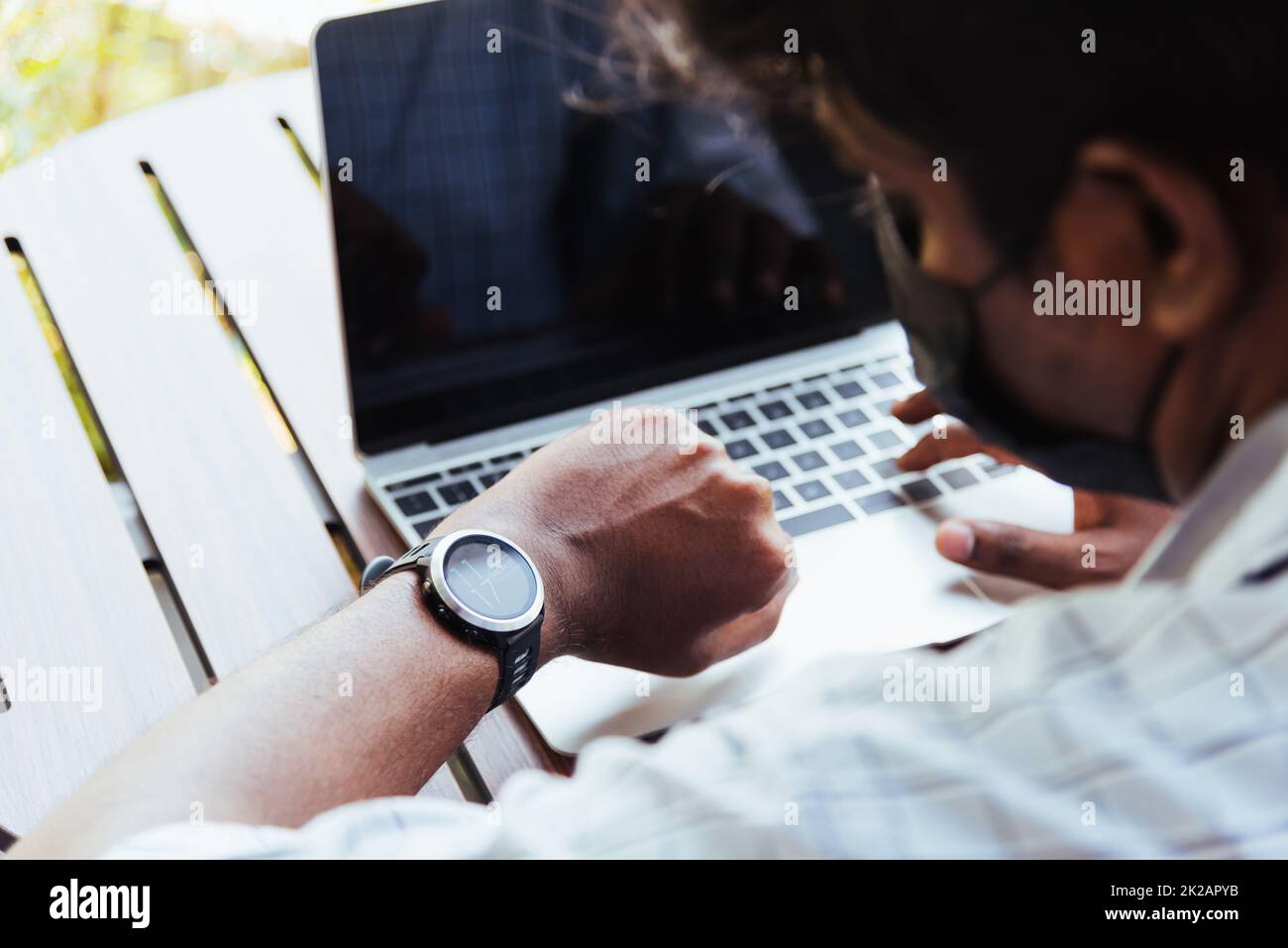 uomo che lavora con un computer portatile e guarda l'orologio durante l'orario della riunione di lavoro della direzione Foto Stock
