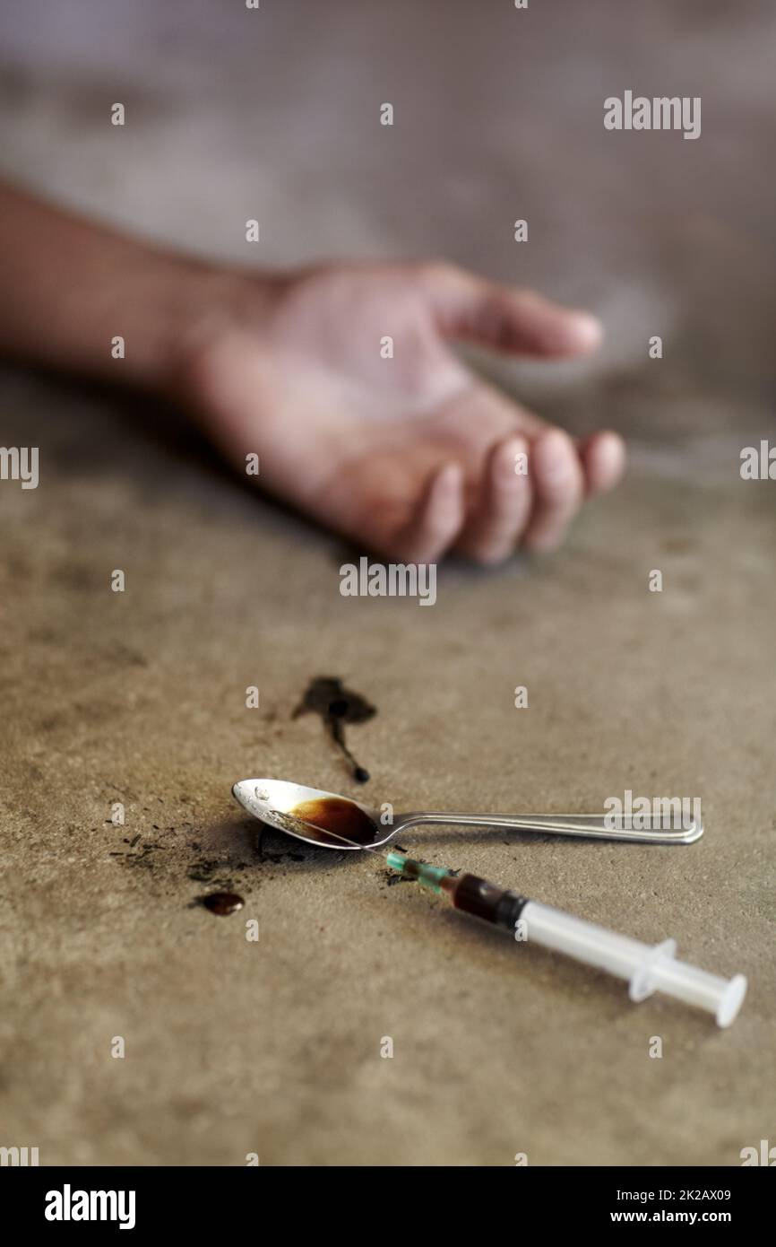 Il suo ultimo alto. Primo piano di un braccio di limp tossicodipendenti con paraphernalia droga che giace accanto ad esso. Foto Stock