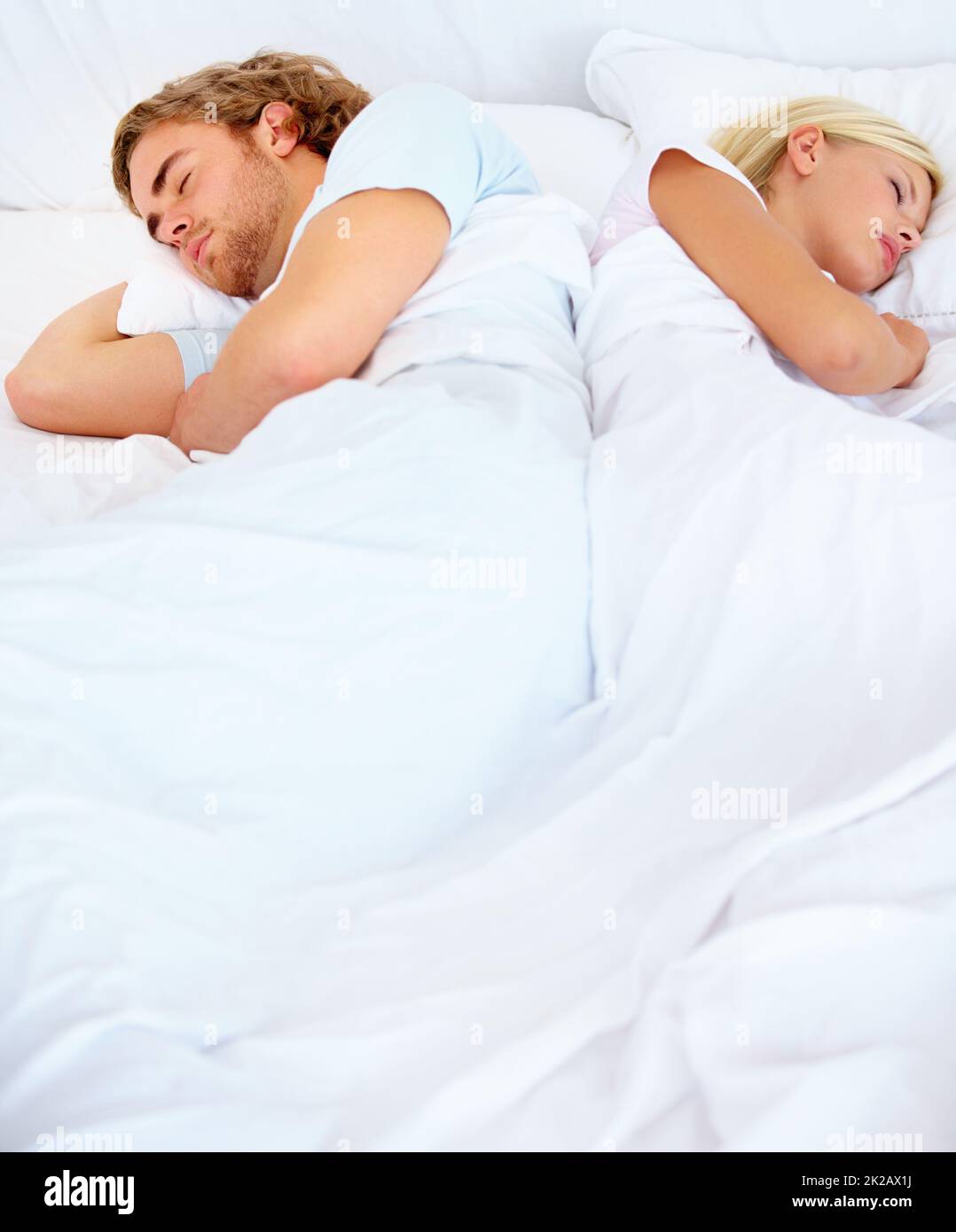 In contrasto l'uno con l'altro. Una giovane coppia che dorme di nuovo a letto. Foto Stock