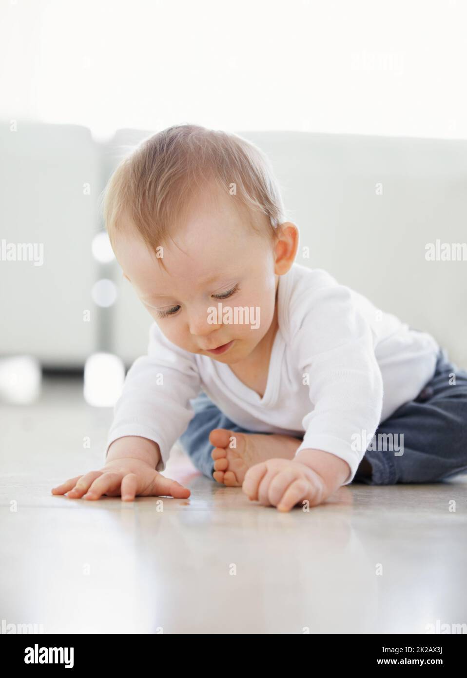 Che cosa è questo. Scatto di un bambino carino che gioca mentre si siede sul pavimento. Foto Stock