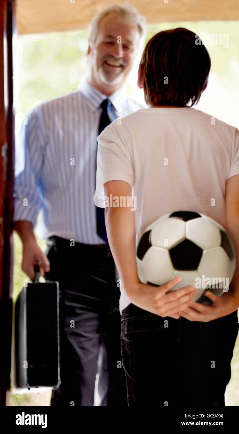 Indovinate cosa stavano facendo dopo il papà di lavoro. Padre che viene a casa da suo figlio in attesa di praticare il calcio. Foto Stock