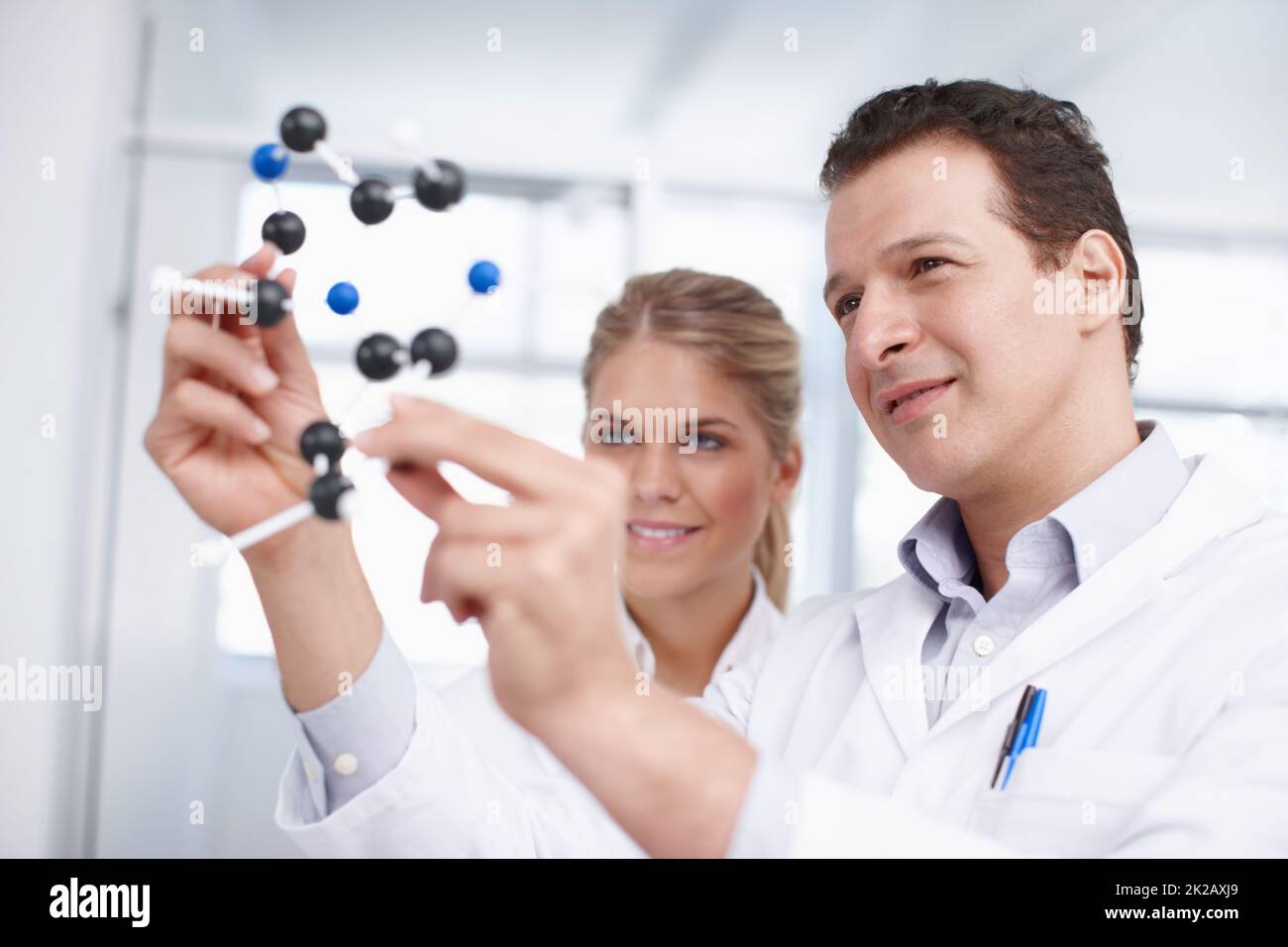 Le strutture molecolari sono affascinanti. Due scienziati che guardano ad un modello di struttura molecolare. Foto Stock