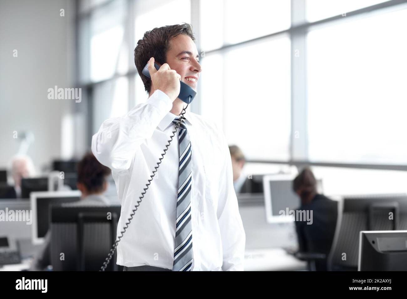 Chiusura della trattativa. Un giovane dirigente d'affari si trova in ufficio mentre si è al telefono. Foto Stock