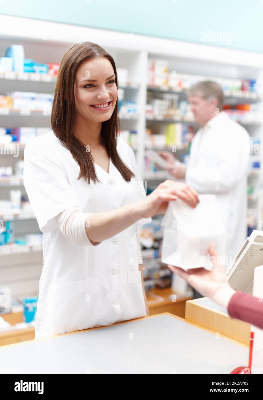 Farmacista che dà il pacchetto al cliente. Ritratto del farmacista consegna del pacchetto al cliente presso il negozio medico. Foto Stock