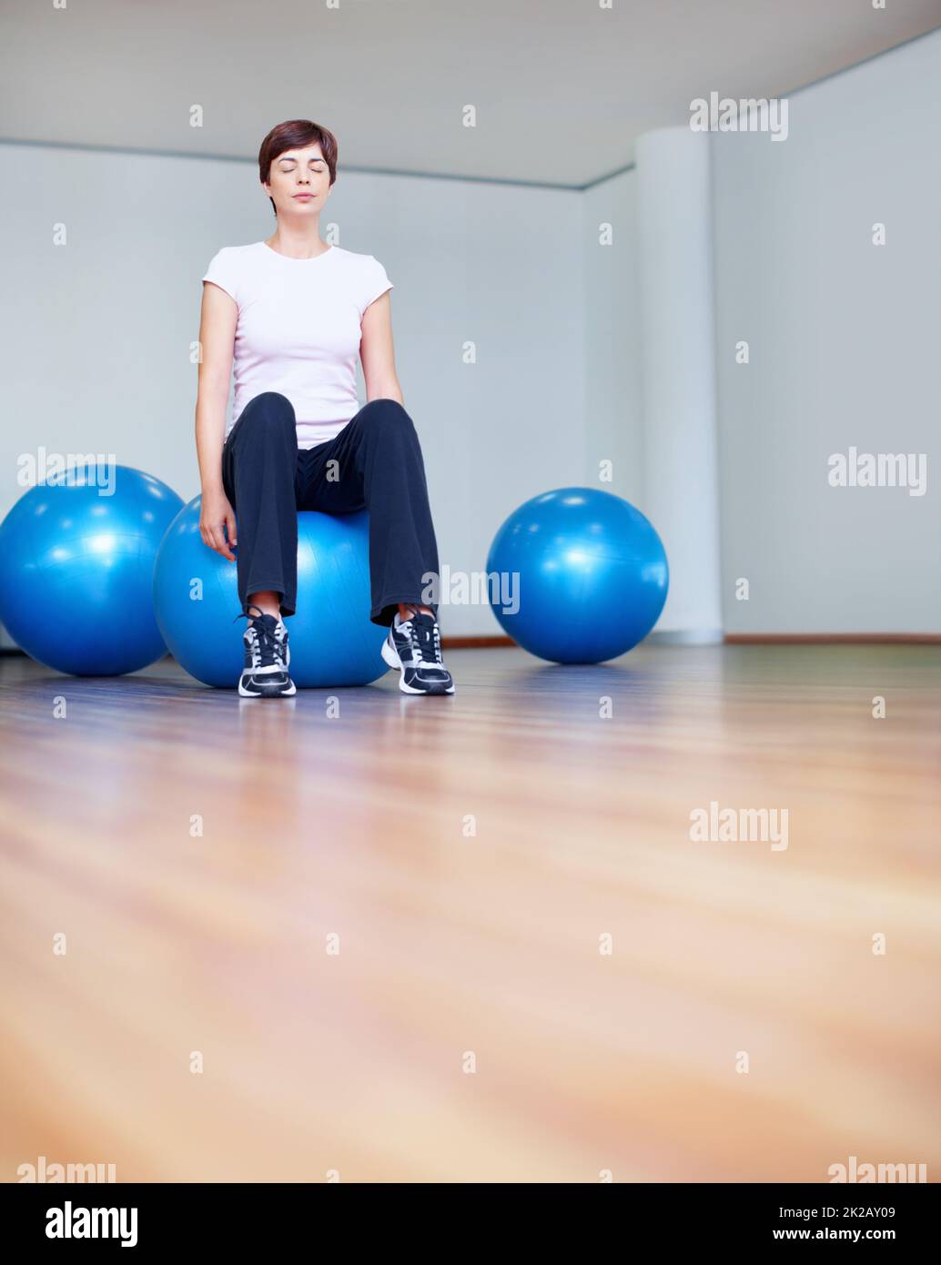 Donna rilassante su pilates palla. Tutta la lunghezza di donna seduta su pilates palla con gli occhi chiusi. Foto Stock