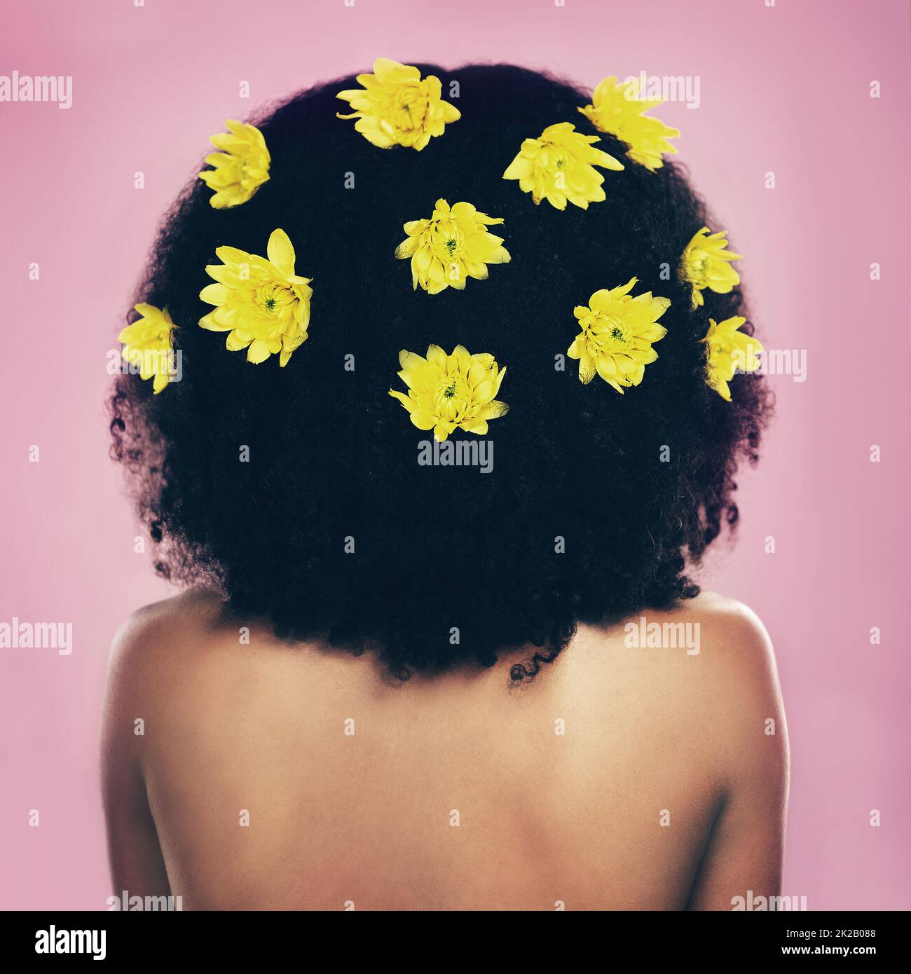 Naturale come ottiene. Scatto retroguarato di una donna in piedi con fiori nei suoi capelli. Foto Stock