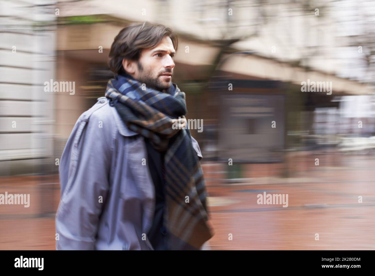 La vita cittadina può essere frenetica. Un bell'uomo che cammina in un'area urbana in fretta. Foto Stock
