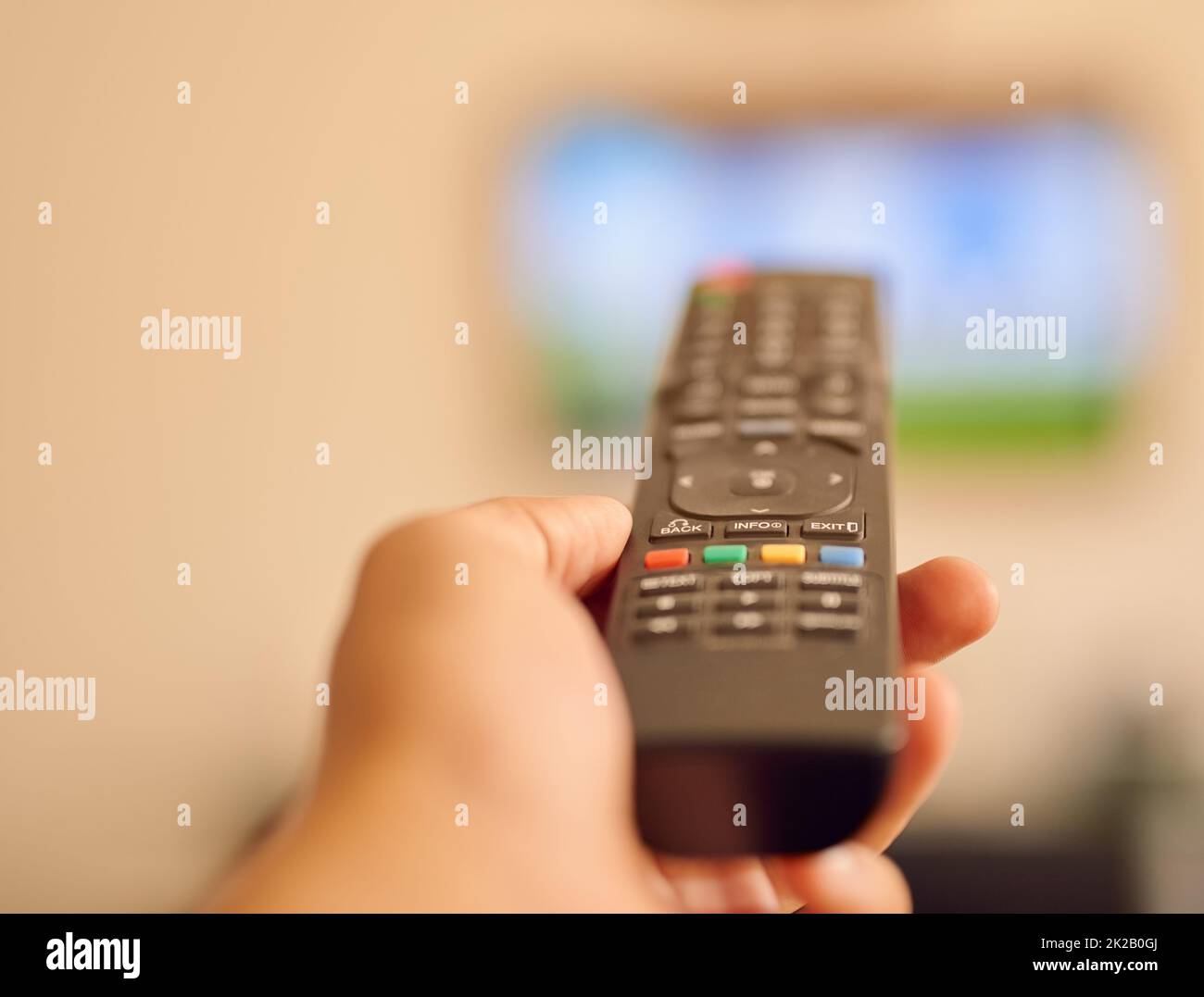 Pronto per iniziare una maratona soap opera. Foto POV di una persona che punta su un televisore a schermo piatto con telecomando. Foto Stock