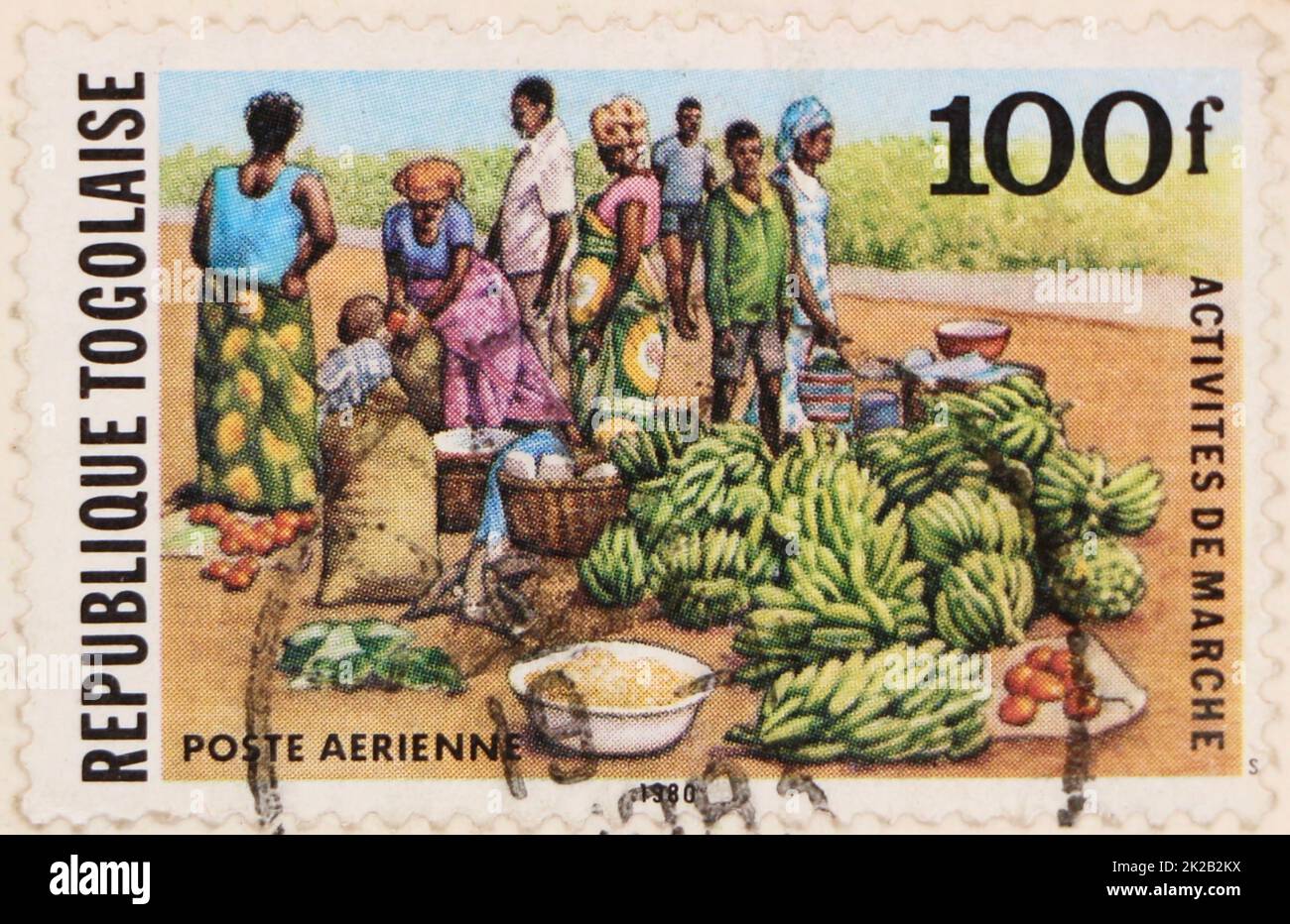 Foto di un francobollo usato della Repubblica Togolese del 100f con un'illustrazione di persone con banane e altri alimenti Foto Stock
