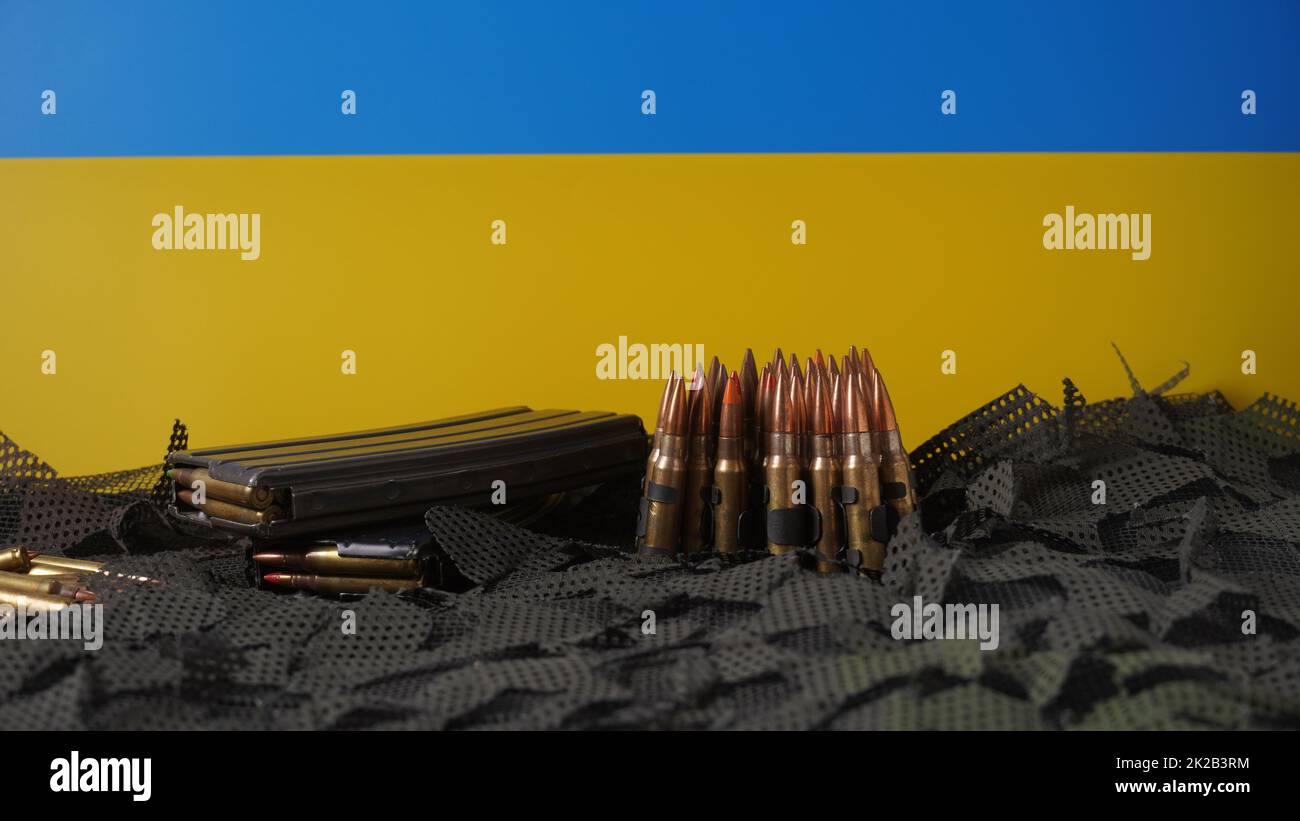 Bandiera blu-gialla dell'Ucraina simbolo nazionale e 5,56mm munizioni, cinghia proiettili mitragliatrici, munizioni fucili in riviste Foto Stock