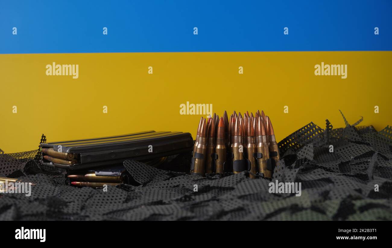 Bandiera blu-gialla dell'Ucraina simbolo nazionale e 5,56mm munizioni, cinghia proiettili mitragliatrici, munizioni fucili in riviste Foto Stock