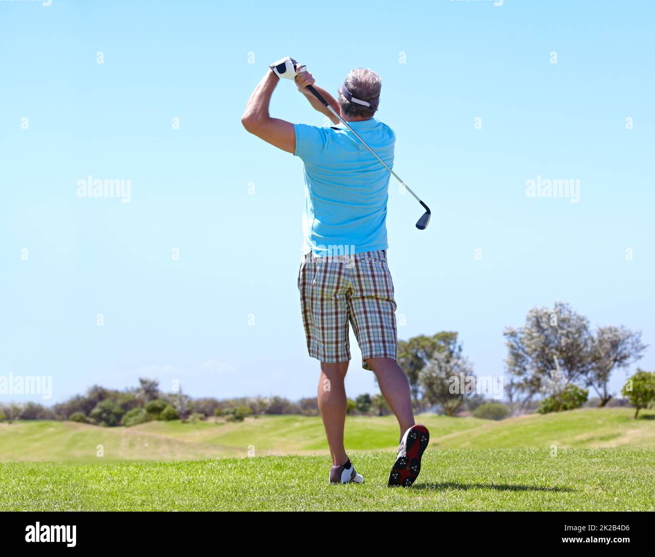 Puntando verso il verde. Vista posteriore di un golfer maschio maturo che gioca un colpo. Foto Stock