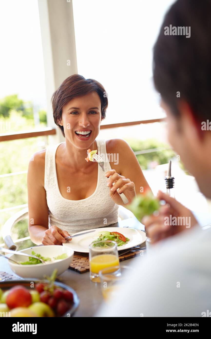 Buon cibo, buon umore. Scatto di una donna attraente che ha pranzato con una persona irriconoscibile. Foto Stock