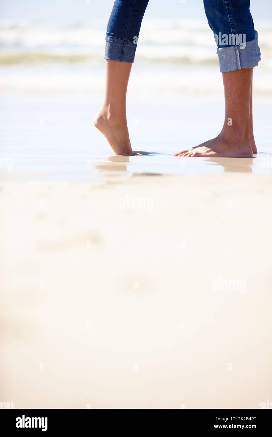 Raggiungi le stelle... o un bacio. Scatto corto di una coppia in piedi vicino al bordo delle acque in una calda giornata di estati. Foto Stock