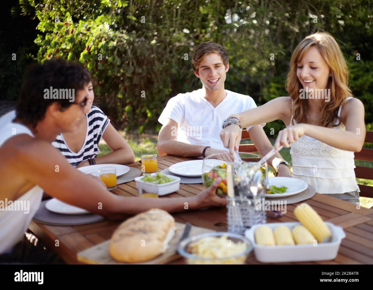 Un po' di sana bontà. Sorridendo i giovani a pranzo con un gruppo di amici - ritratto. Foto Stock