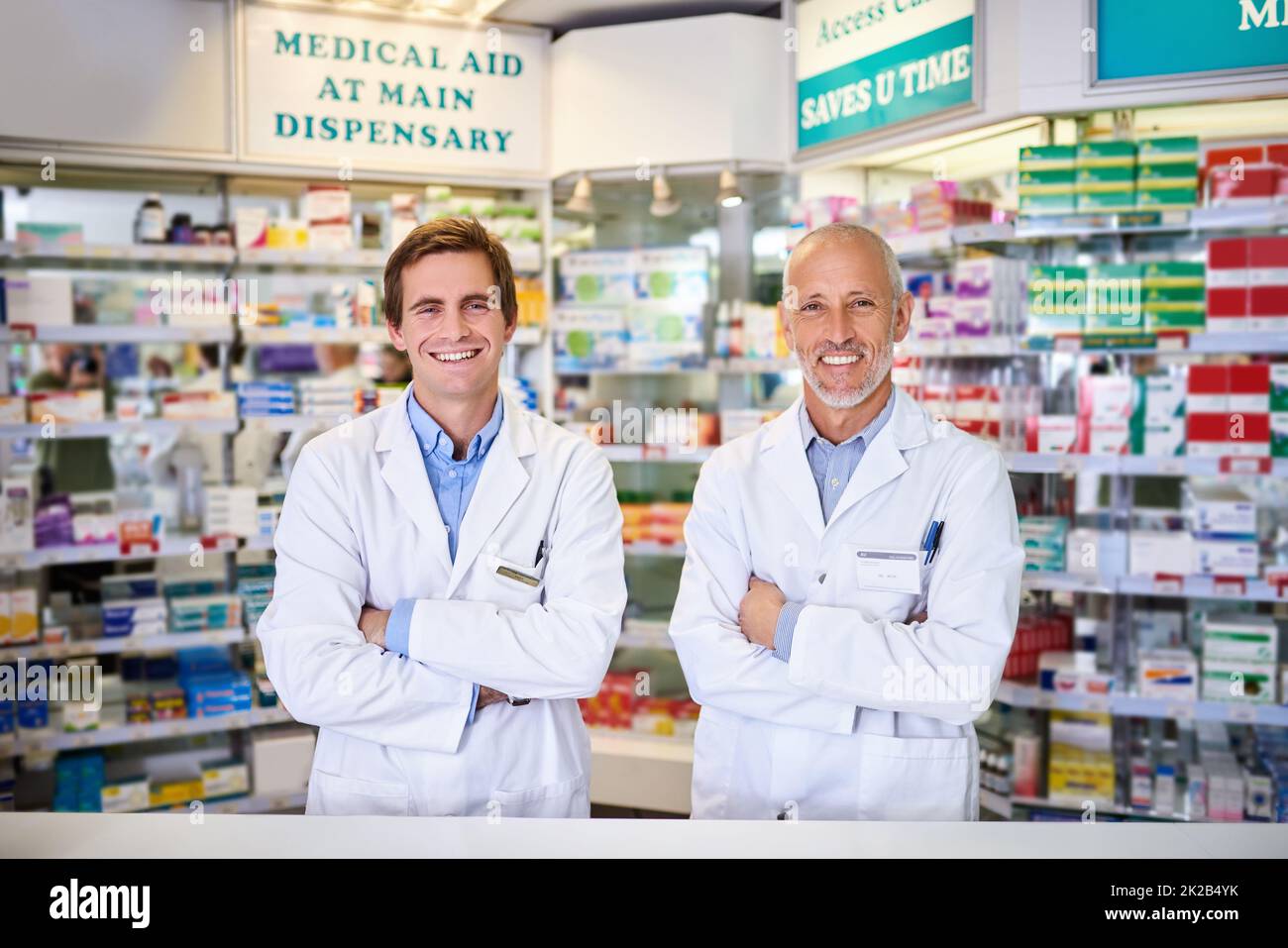 Il nostro servizio di qualità è gratuito. Ritratto di due farmacisti maschi che lavorano in un chimico. Foto Stock