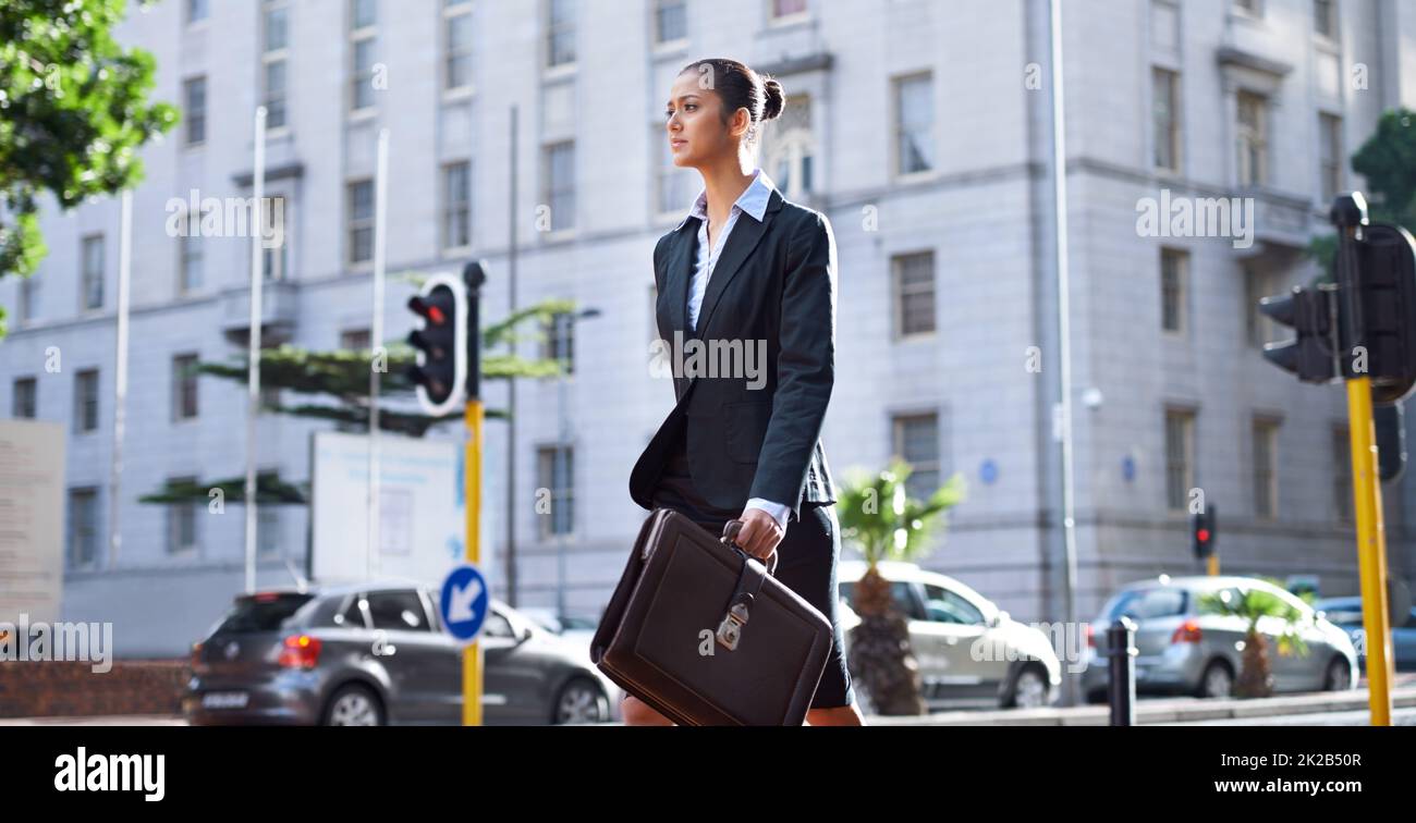Alla sua prossima riunione. Una giovane donna d'affari che cammina in città per andare al lavoro. Foto Stock