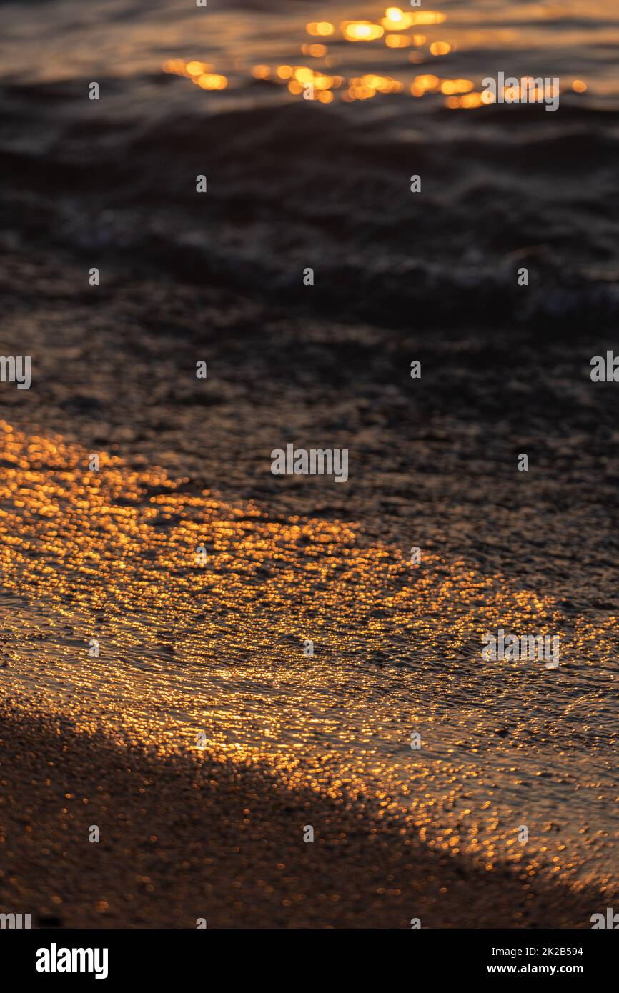 Ripple acqua mare oceano superficie con luce tramonto dorato. Primo piano dell'onda di mare Foto Stock