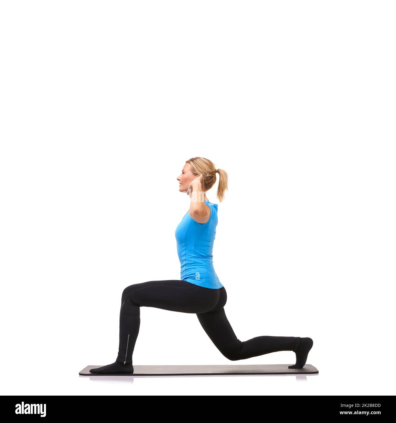Per il fitness. Una giovane donna che esegue affondi sul tappeto da allenamento mentre è isolata su bianco. Foto Stock
