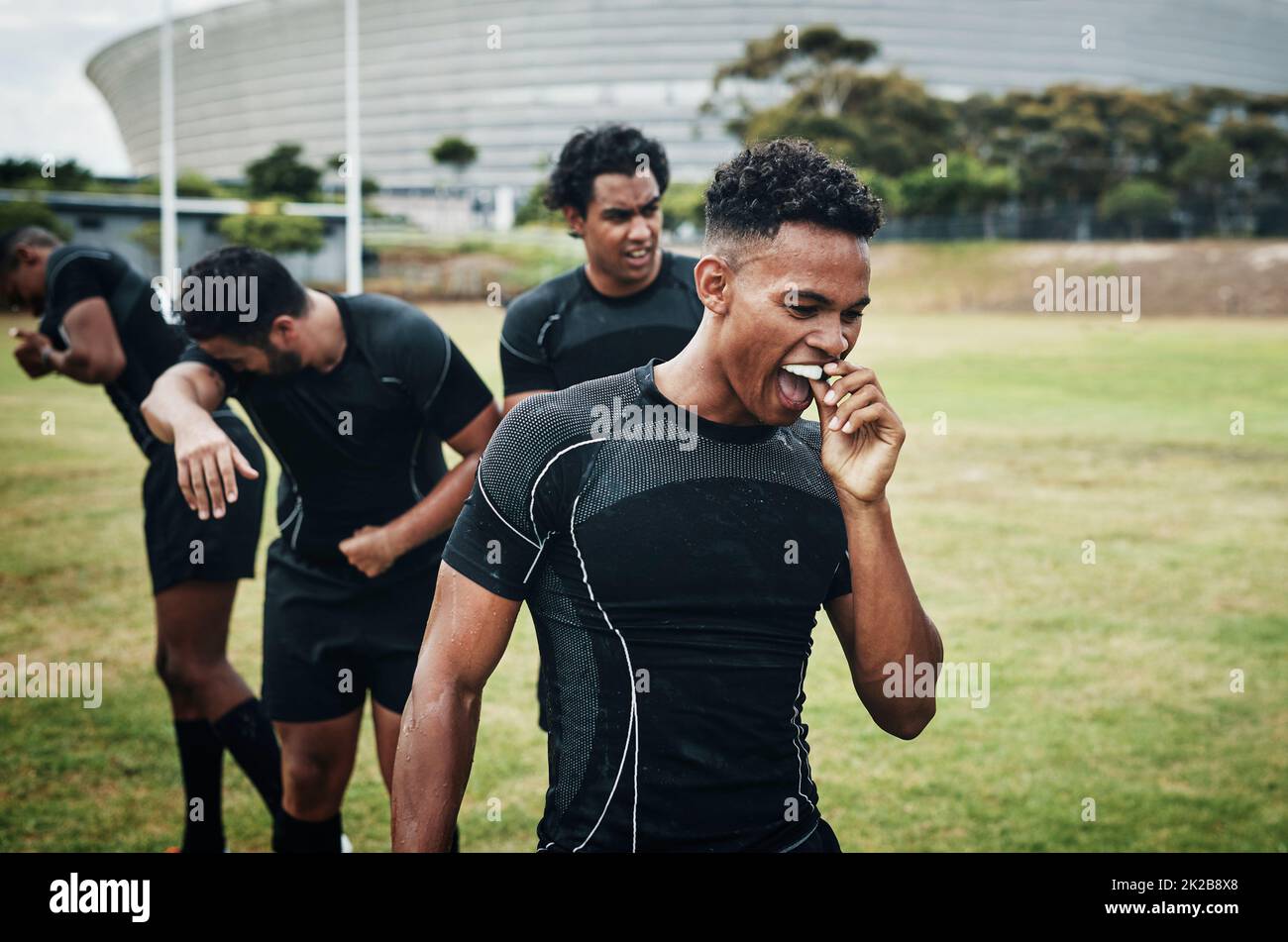 Il suo tempo di dimezzamento. Scatto corto di un bel giovane giocatore di rugby che rimuove il suo proteggisbocca durante metà tempo sul campo. Foto Stock