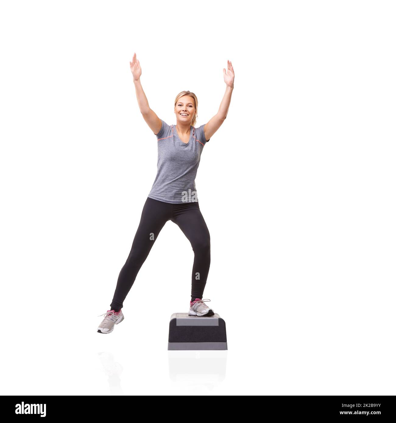 Raggiungere i suoi obiettivi di fitness. Una giovane donna sorridente che fa aerobica su un punto aerobico contro uno sfondo bianco - K-step. Foto Stock