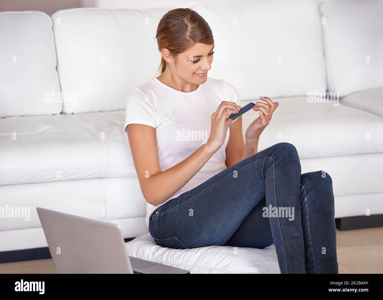 Il lavoro può aspettare, beautys modo più importante. Scatto ritagliato di una giovane donna attraente seduta giù e limando le sue unghie a casa. Foto Stock
