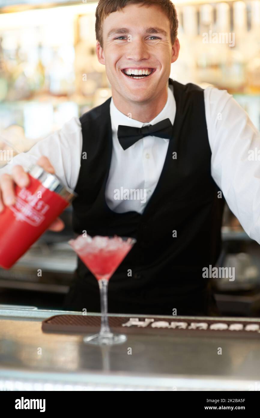 Quenching qualsiasi sete di ladys. Il giovane bel barman ridendo e sorridendo mentre si stendesse un cocktail delizioso e gustoso. Foto Stock