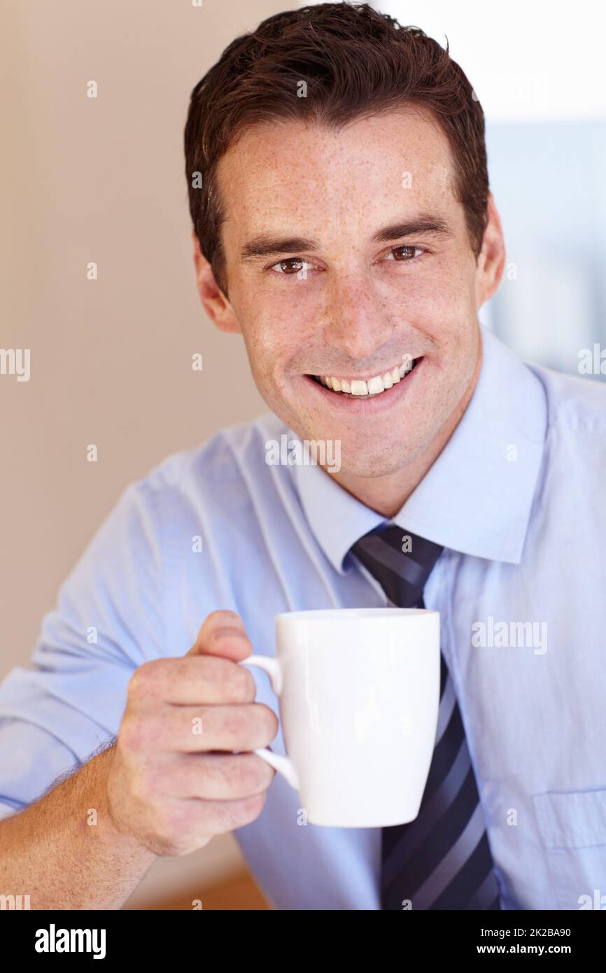 Gustando il caffè del mattino. Sorridente giovane uomo d'affari che si gode la sua pausa caffè. Foto Stock