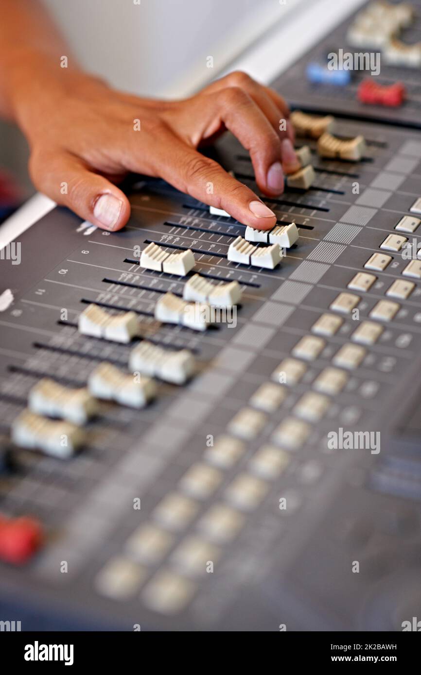 Perfezionare il mix. Immagine ingrandita di una mano che sposta un cursore su un banco di miscelazione. Foto Stock