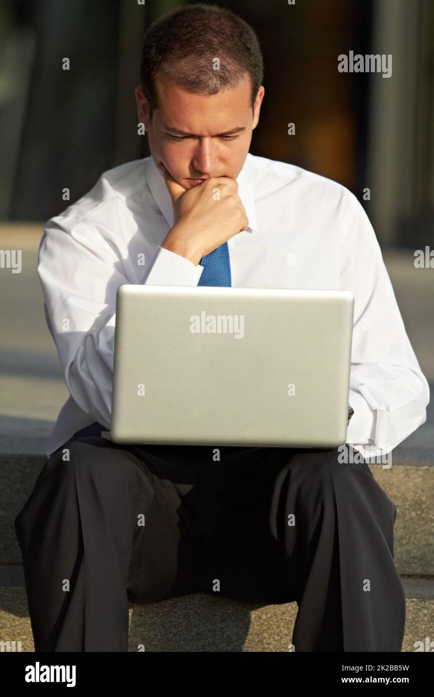 Cosa fare. Un uomo d'affari attento seduto sui gradini e utilizzando il suo laptop. Foto Stock