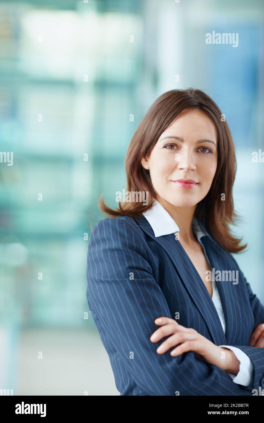 La sua carriera sta solo salendo. Attraente dirigente di affari femminile in piedi sul lavoro. Foto Stock