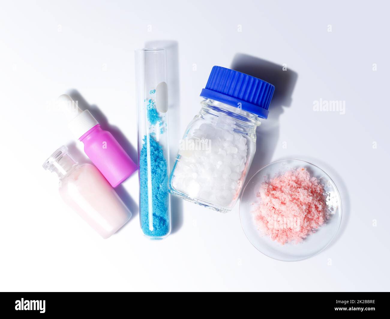 Crema di bellezza, siero, solfato di rame(II) in provetta e cera microcristallina in contenitore di vetro posizionare accanto al sale rosa himalayan in vetro da orologio chimico. Vista dall'alto Foto Stock