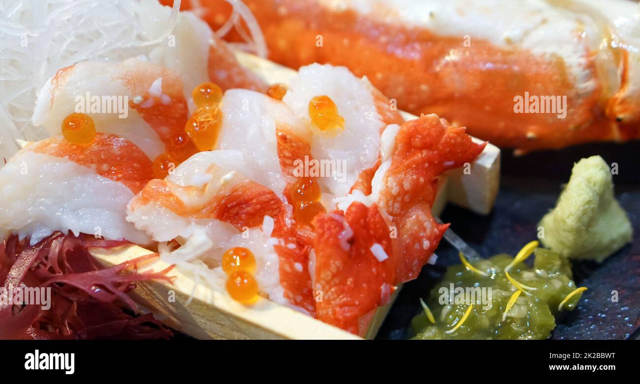 Sashimi Alaska King Crab top con Ikura su piatto di legno. Servito con alghe maufunori, rafano grattugiato, kizami wasabi e wasabi freschi. Foto Stock