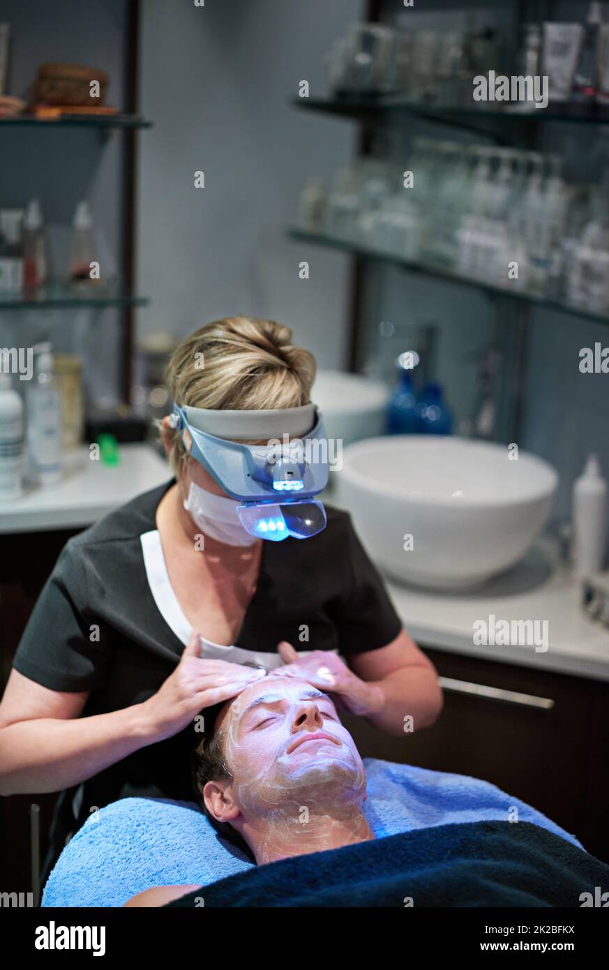 La pelle giovane sta arrivando presto. Un uomo che ottiene un trattamento facciale ad una clinica di bellezza. Foto Stock