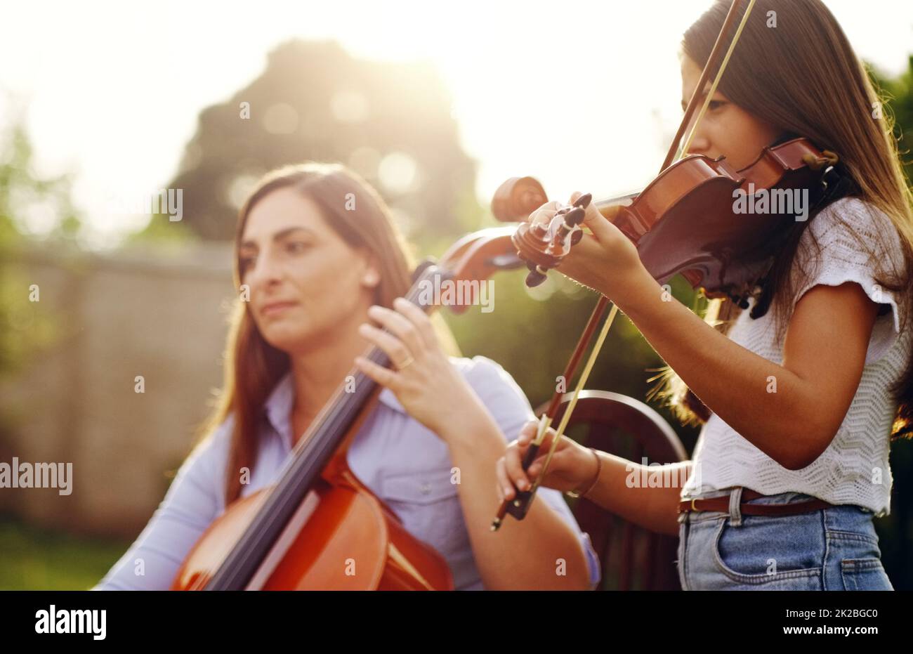 Musica in famiglia. Scatto corto di una madre e di una figlia che suonano strumenti musicali insieme nel cortile. Foto Stock